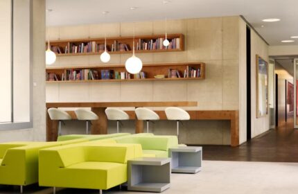 Art'otel Cologne by Park Plaza, a Radisson hotel. Lobby lounge area with bookshelves, desks, and lime green seating. Gay-friendly hotel.