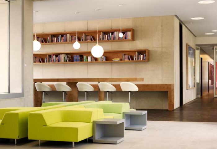 Art'otel Cologne by Park Plaza, a Radisson hotel. Lobby lounge area with bookshelves, desks, and lime green seating. Gay-friendly hotel.