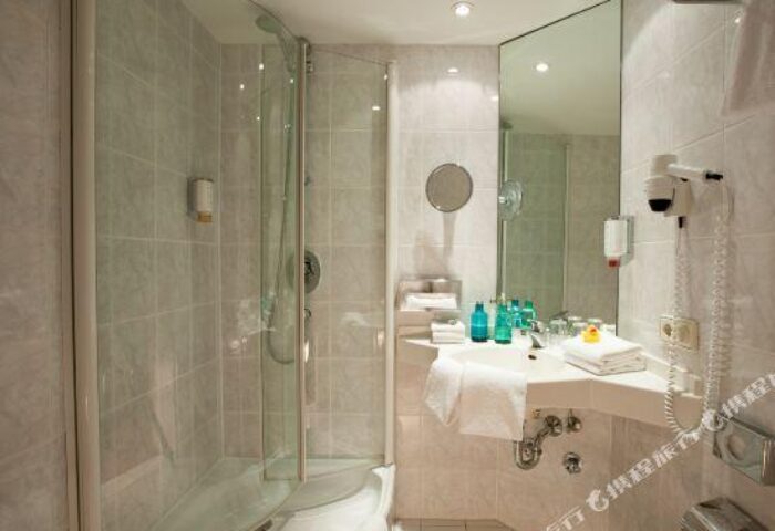 Bathroom at carathotel Munchen City, a gay-friendly hotel. Features a shower, sink with amenities, and a mirror. Clean, modern design.