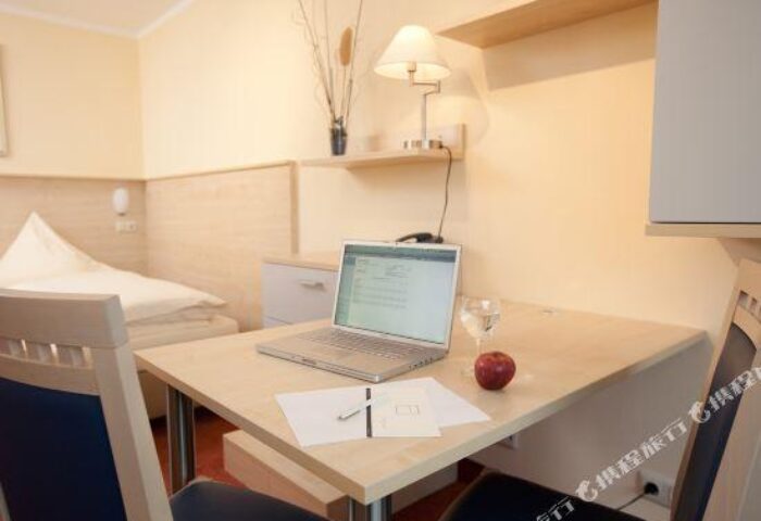 Carathotel Munchen City room interior. Laptop, glass of water, & apple on desk. Gay-friendly hotel in Munich, Germany for gay men travelers.