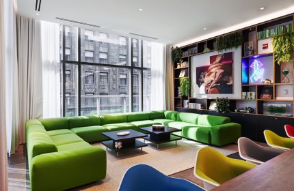 citizenM Chicago Downtown gay-friendly hotel: Modern lounge area with green sofa, colorful chairs, and city views. Stylish design.