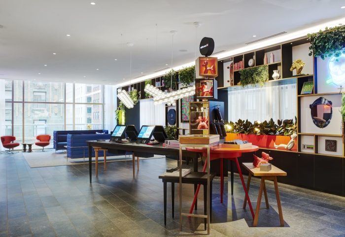citizenM Chicago Downtown lobby, a gay-friendly hotel. Modern design with colorful decor, plants, and city views. Check-in kiosks visible.