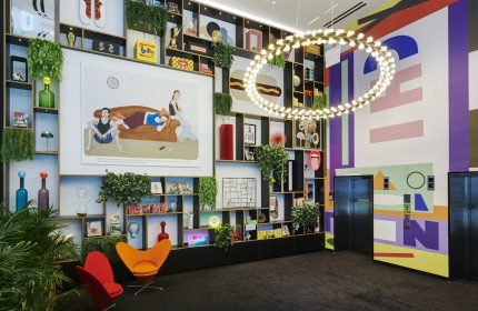 citizenM Chicago Downtown's gay-friendly hotel lobby. The interior features colorful decor, a large bookshelf, and modern design elements.