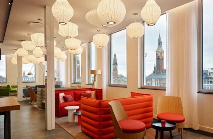 citizenM Copenhagen Radhuspladsen hotel interior. Gay-friendly hotel lounge area with stylish lighting, red seating, and city views.