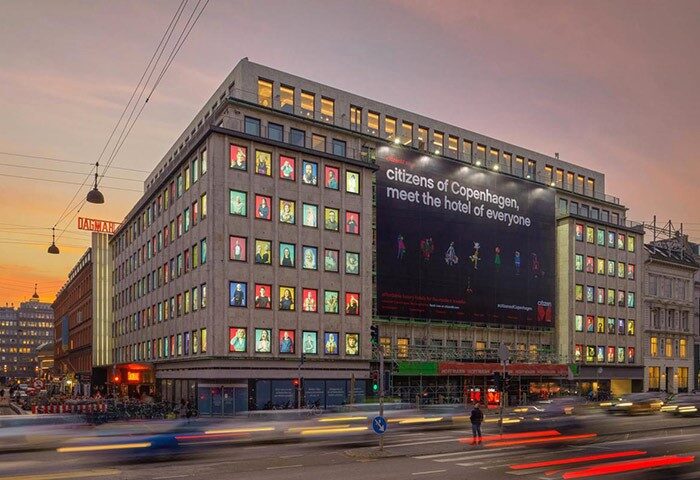citizenM Copenhagen Radhuspladsen hotel exterior view. Gay-friendly hotel with colorful window portraits and a large ad. Radhuspladsen location.
