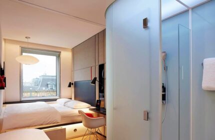 citizenM Copenhagen Radhuspladsen hotel room interior. Modern design, bed, desk, and frosted glass shower. Gay-friendly hotel for travelers.