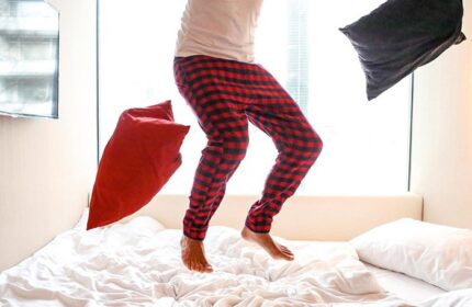 Man jumping on bed in citizenM Copenhagen Radhuspladsen hotel room. Gay-friendly hotel with fun, modern design, and playful atmosphere.