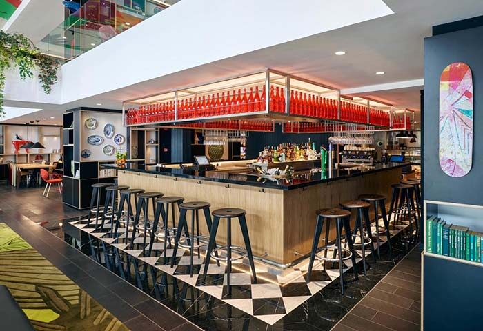 citizenM Kuala Lumpur Bukit Bintang's bar area. This gay-friendly hotel features a modern design with a bar stocked with red bottles.