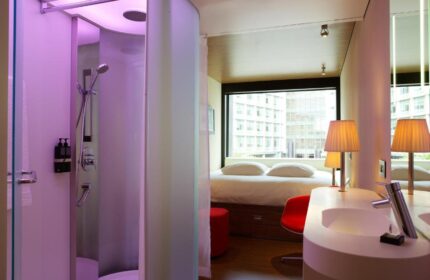 citizenM London Bankside hotel room. Modern design with shower, sink, bed, and city view. Gay-friendly hotel for your London travel.