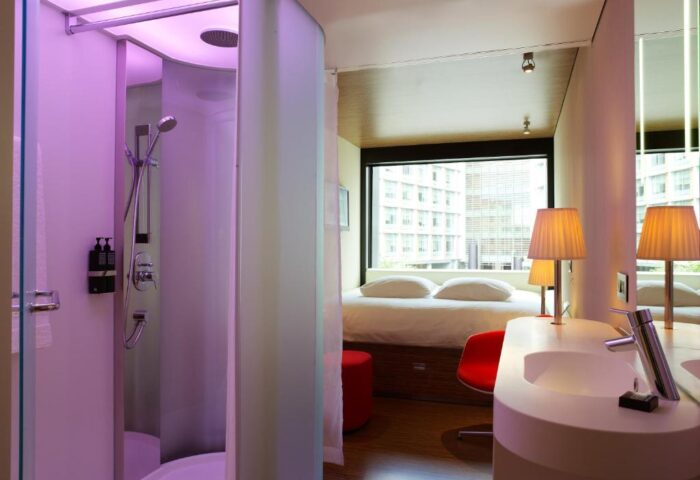 citizenM London Bankside hotel room. Modern design with shower, sink, bed, and city view. Gay-friendly hotel for your London travel.
