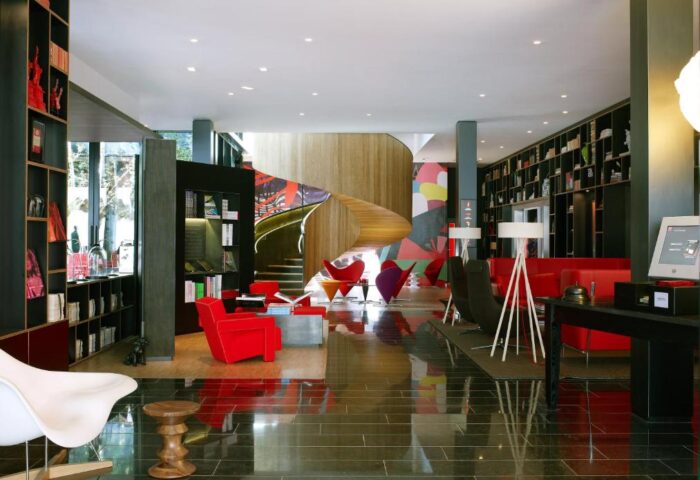 citizenM London Bankside's lobby. Gay-friendly hotel with bookshelves, red chairs, & spiral stairs. Modern design for gay men travel.