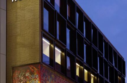 citizenM London Bankside hotel exterior at dusk. Modern architecture, windows, and illuminated signage. Gay-friendly hotel in London.