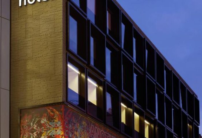 citizenM London Bankside hotel exterior at dusk. Modern architecture, windows, and illuminated signage. Gay-friendly hotel in London.
