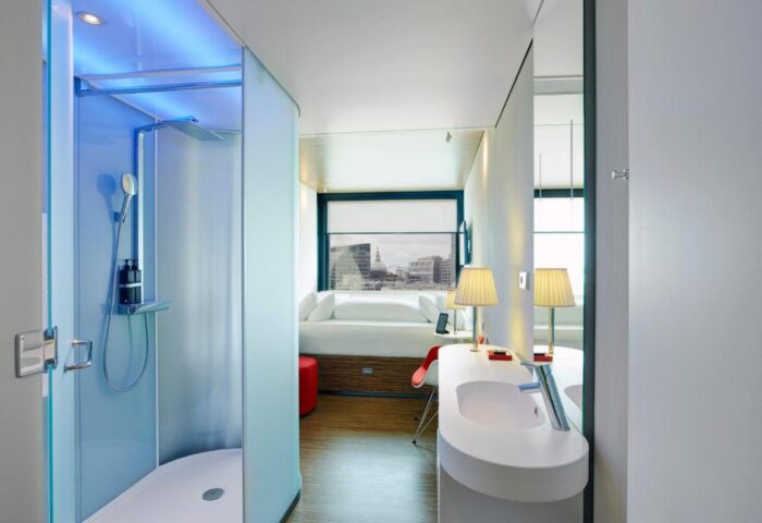 citizenM London Shoreditch gay-friendly hotel room. Modern design, shower, sink, bed, and city view. Ideal for gay men's travel in London.