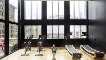 citizenM Los Angeles Downtown gay-friendly hotel gym. Exercise bikes, rowing machine, and treadmills with city view. Modern fitness for gay men.