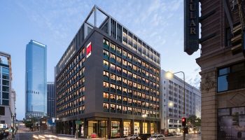 citizenM Los Angeles Downtown hotel exterior. Gay-friendly hotel architecture in LA. Modern design, street view, and city skyline.