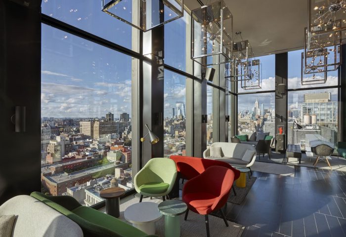 citizenM New York Bowery hotel interior. Colorful chairs, sofas, and city views. Gay-friendly hotel for gay men travel advice.
