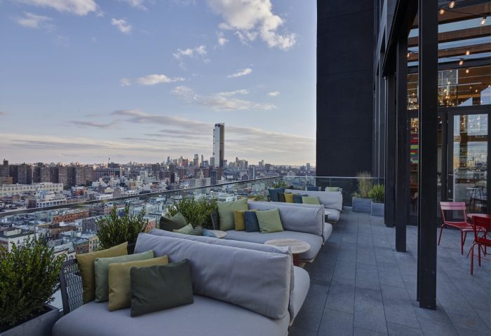 citizenM New York Bowery, a gay-friendly hotel. Rooftop lounge area with sofas and city views. Great for gay travelers in NYC.