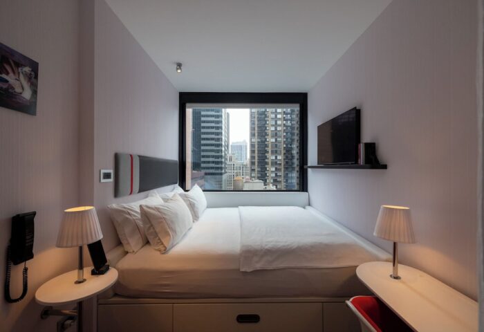 citizenM New York Times Square hotel room. Gay-friendly hotel with city views. Modern design, comfortable bed, and sleek furnishings.