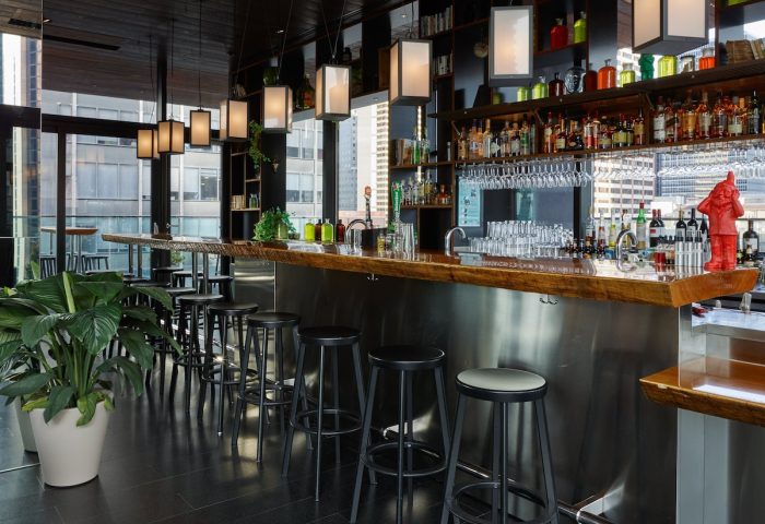 citizenM New York Times Square gay-friendly hotel bar. Modern design with stools, liquor selection, and city view. Great for gay travel.