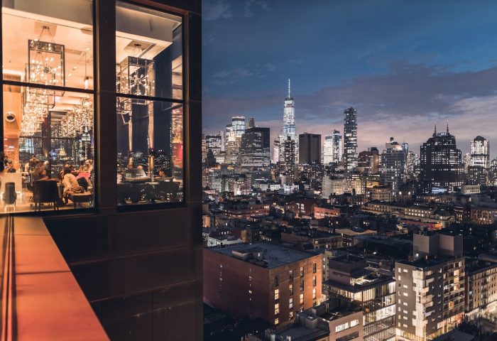 citizenM New York Times Square gay-friendly hotel view. Night cityscape with illuminated skyscrapers and hotel interior.