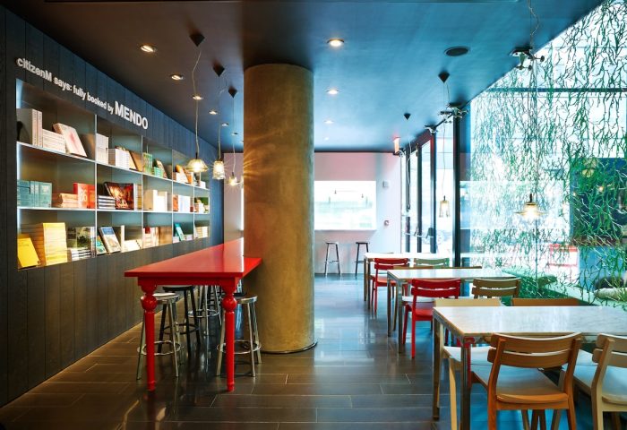 citizenM New York Times Square gay-friendly hotel interior. Tables, chairs, and a bookshelf create a stylish, welcoming space.