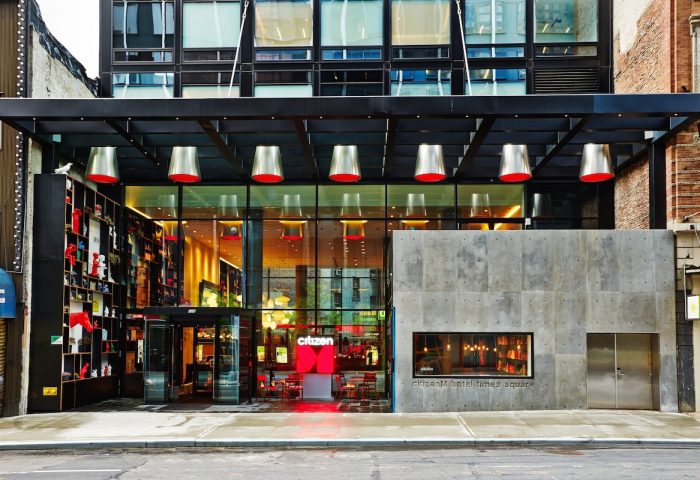 citizenM New York Times Square entrance. Gay-friendly hotel with modern design, red accents, and glass facade. A great choice for gay travelers.