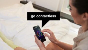 citizenM Taipei North Gate: Guest uses phone in bed. Gay-friendly hotel offers contactless service. Modern room, comfortable stay.