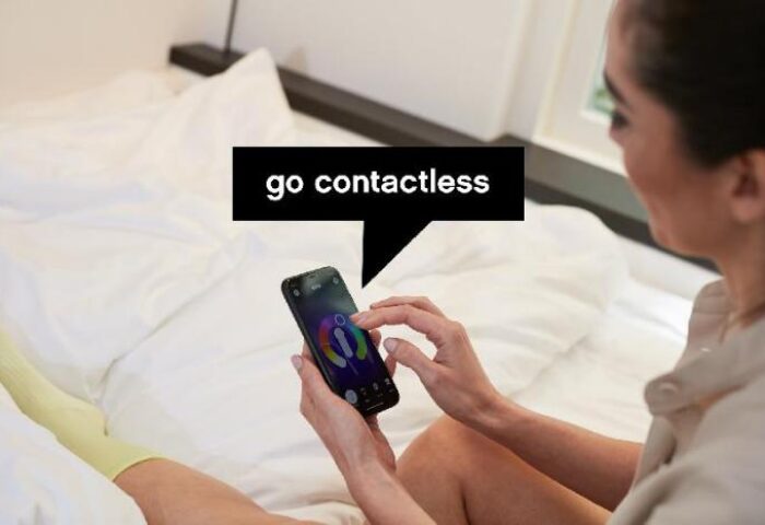 citizenM Taipei North Gate: Guest uses phone in bed. Gay-friendly hotel offers contactless service. Modern room, comfortable stay.