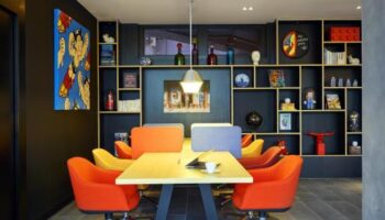 citizenM Taipei North Gate meeting room. Colorful, modern design with orange chairs, a table, and a stylish bookshelf. Gay-friendly hotel.