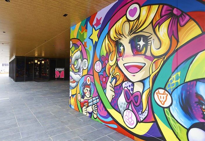 citizenM Taipei North Gate's exterior features vibrant, gay-friendly art. The hotel entrance is visible, inviting travelers.