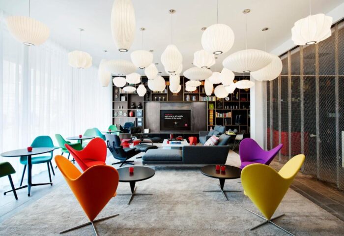 citizenM Tower of London's gay-friendly hotel lounge. Colorful chairs, modern lighting, & stylish decor create a welcoming space.