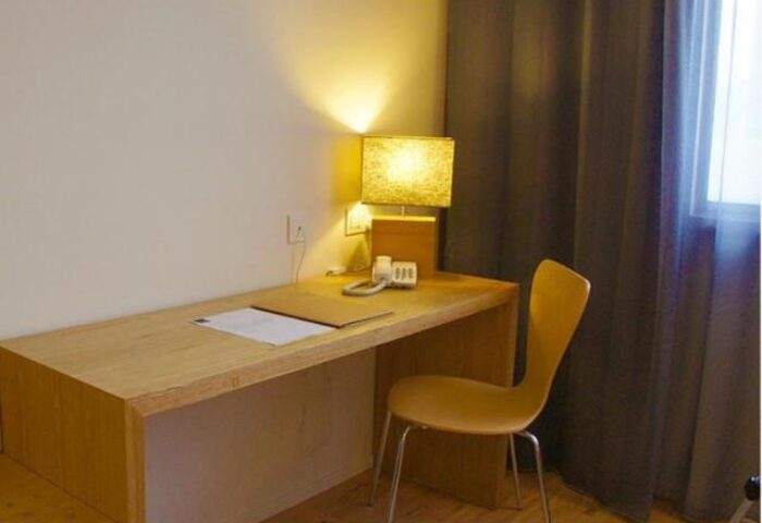 De King Boutique Hotel KLCC desk area. Gay-friendly hotel room features a desk, lamp, chair, and window. Modern interior design.