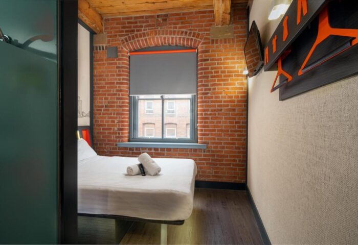easyHotel Manchester room. Gay-friendly hotel room with exposed brick wall, window, bed, and modern decor. Ideal for gay travelers in Manchester.