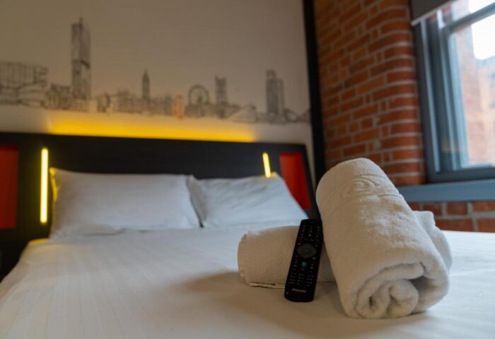 easyHotel Manchester room. Gay-friendly hotel with skyline art, brick wall, towels, and remote. Comfortable, modern stay for gay travelers.