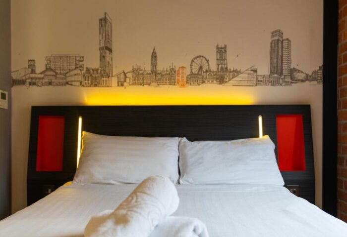 easyHotel Manchester room featuring a bed with Manchester skyline art above the headboard. Gay-friendly hotel for gay men travel.