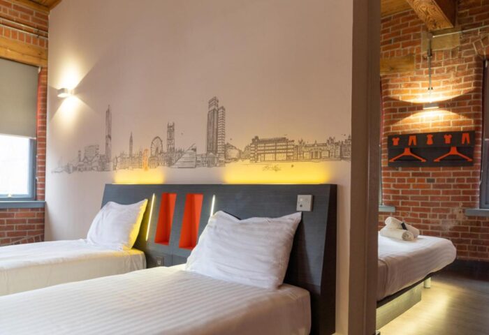 easyHotel Manchester room. Gay-friendly hotel featuring twin beds, exposed brick, and a Manchester skyline mural. Budget travel for gay men.