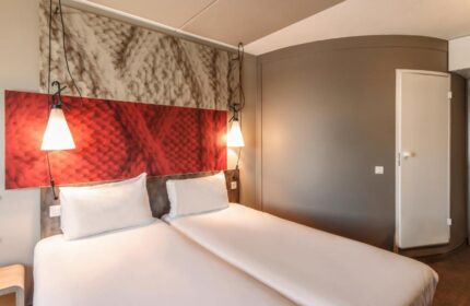 Ibis Amsterdam Centre hotel room, pet-friendly. Double bed with white linens. Modern design, gay-friendly hotel.