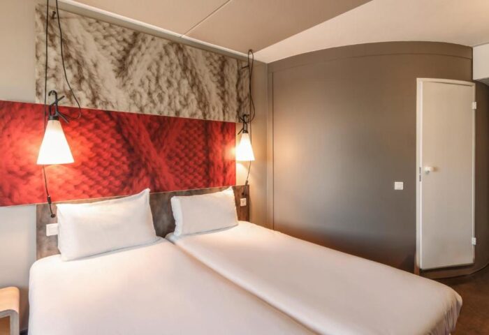 Ibis Amsterdam Centre hotel room, pet-friendly. Double bed with white linens. Modern design, gay-friendly hotel.