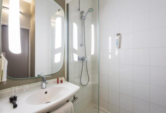 Ibis Amsterdam Centre gay-friendly hotel bathroom. Sink, mirror, and shower in a pet-friendly room. Modern design for gay travel.