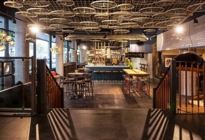 Ibis Amsterdam Centre hotel bar area with tables, chairs, and bicycle wheel ceiling decor. Gay-friendly, pet-friendly hotel interior.