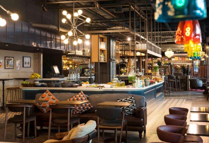 Ibis Amsterdam Centre's pet-friendly, gay-friendly hotel bar area. Modern design with unique lighting and seating. A welcoming space.