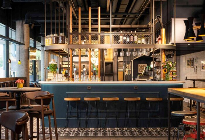 Bar area at the gay-friendly Ibis Amsterdam Centre. Pet-friendly hotel with stools, tables, and a unique industrial design. Amsterdam travel.