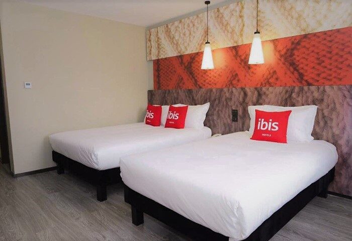 Ibis Beijing Tuanjiehu gay-friendly hotel room. Two beds with white linens and red pillows. Modern design, perfect for gay travelers.