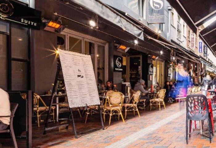Outdoor dining at a gay-friendly hotel, ibis Melbourne Central. Street view with tables, chairs, and menu board. Melbourne travel advice.
