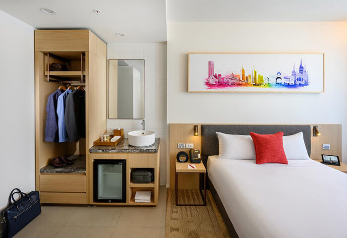 Ibis Melbourne Central hotel room. Gay-friendly hotel with a bed, closet, sink, and colorful Melbourne skyline art. Modern design.