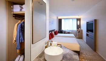 Ibis Melbourne Central gay-friendly hotel room. Two beds with red pillows, sink, mirror, closet with clothes. Ideal for gay men travelers.
