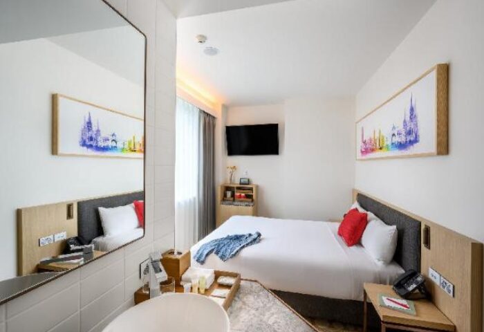 Ibis Melbourne Central hotel room. Gay-friendly travel option with modern decor. Double bed, colorful artwork, and bathroom amenities.