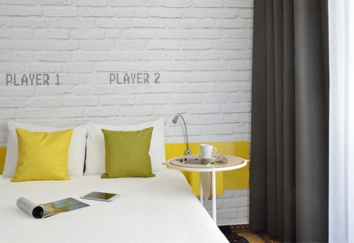 Ibis Styles Budapest Center guest room with Player 1 & Player 2 on the brick wall. Gay-friendly hotel for gay men travel in Budapest.