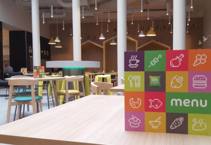 Ibis Styles Budapest Center restaurant interior. Menu stand with colorful icons. Gay-friendly hotel dining area with modern design.